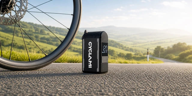 Compact black electric pump beside a bicycle on a road