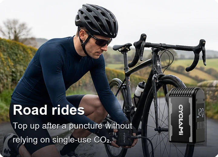 Cyclist using a compact electric pump beside a road bike